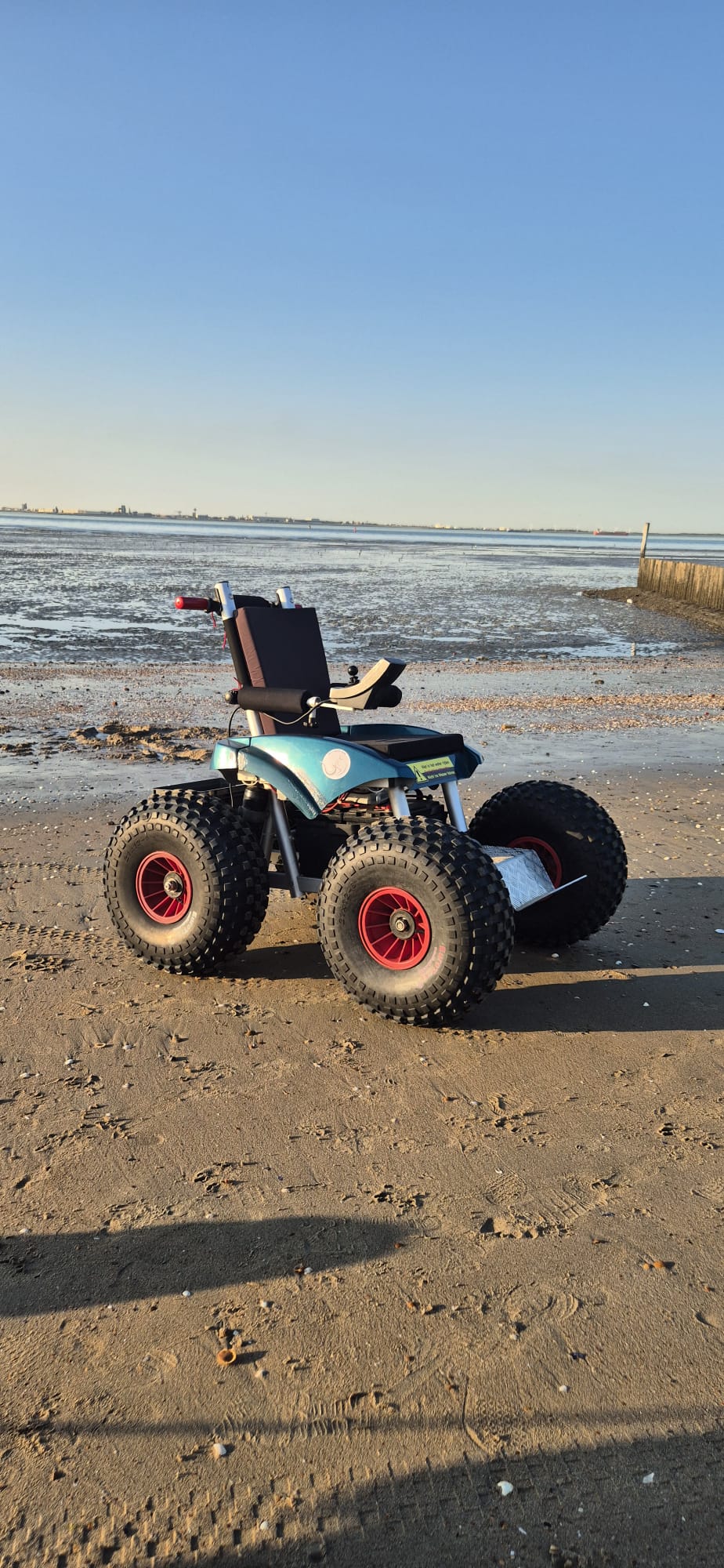 Elektrische strandrolstoel Cadweazle met grove terreinbanden op het strand aan de Zeeuws-Vlaamse kust